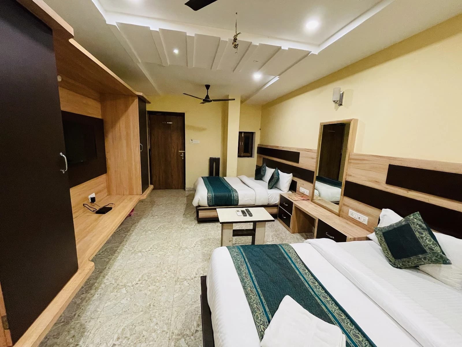 Two beds with green runners and a small table in a Hotel Augusto guest room