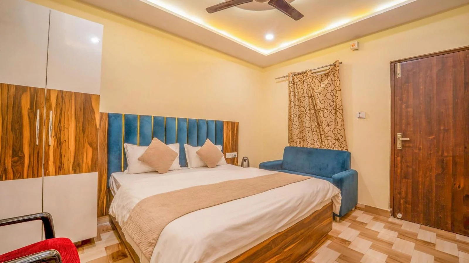 A double-bed room at Hotel Augusto with warm wood finishes and blue upholstery